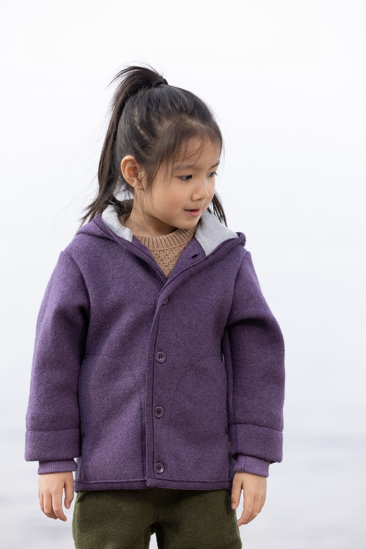 Asiatisches Mädchen in disana Walk-Jacke Auberbergine und Walk-Hose in Oliv am Seeufer - Mädchen schaut nach unten.